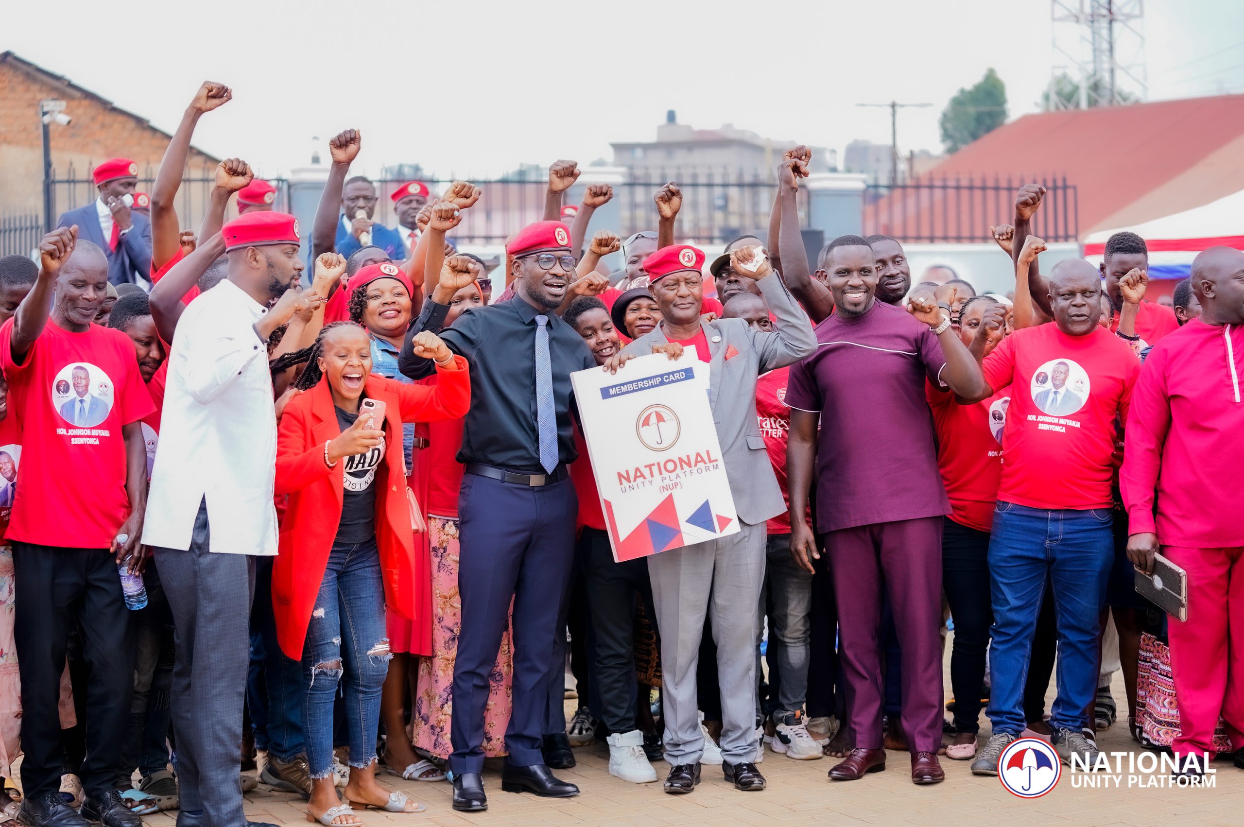 Robert Kyagulanyi, known as Bobi Wine, stands at the National Unity Platform (NUP) headquarters, addressing over 270 new members and leaders joining the party. He is surrounded by NUP officials and members of the creative community. New motor vehicles are displayed, symbolizing the party's commitment to mobilization across Uganda's four regions. Kyagulanyi speaks passionately about the need to liberate Uganda from its current governance crisis and emphasizes the role of each member in advancing the cause for freedom, democracy, and prosperity in the country.