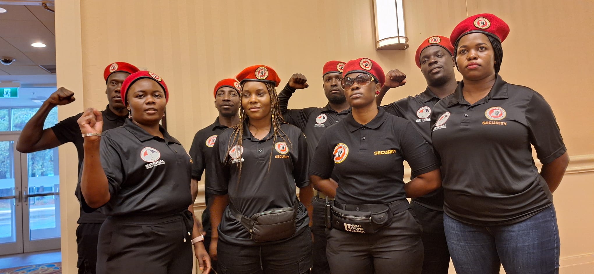 NUP security team members, dressed in black uniforms and red berets, stand vigilant during the Toronto event, ensuring safety and order for all attendees.